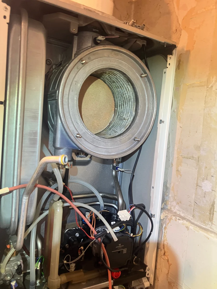 Boiler stripped down during a service, showing the opened combustion chamber, pipework and wiring