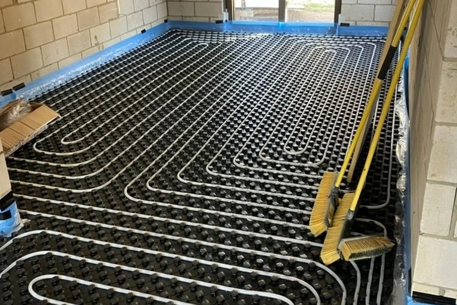 Wet underfloor heating pipe laid across a full room on castellated insulation panel